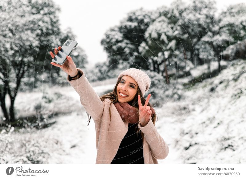 smiling woman taking selfie in winter take photo forest smartphone snow memory woods moment warm clothes stroll scenery using device cold nature mobile gadget