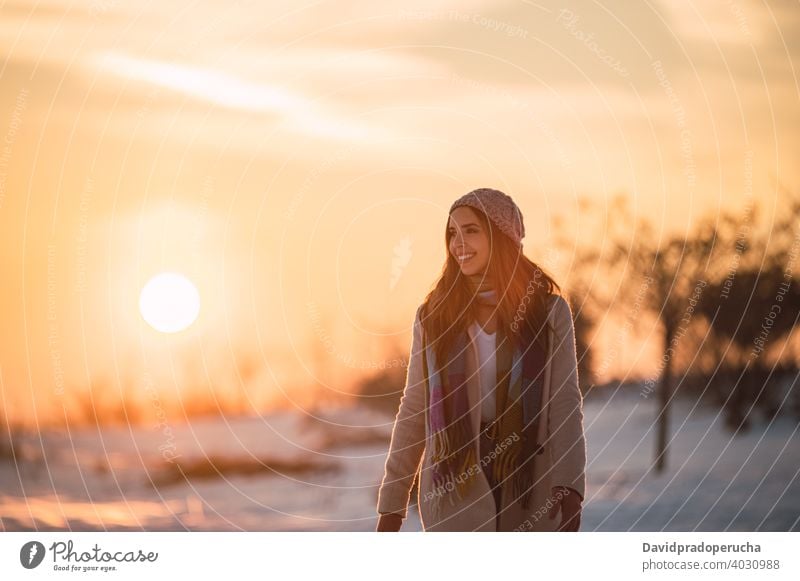 Woman walking on snowy field at sunset winter countryside happy nature season enjoy glad fresh cold cheerful stroll smile sundown recreation lifestyle weather