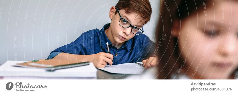 Teen writing in notebook at school teen student looking camera classroom banner web header panorama panoramic copy space smart studious education people young