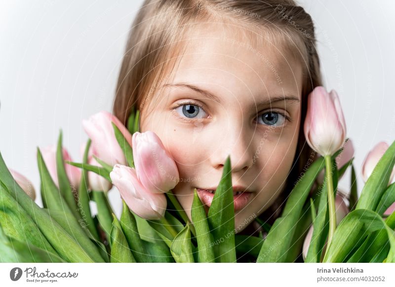 Little beautiful happy girl holding bunch of pink, green tulips in hands. Bouquet, congratulations to the holiday of mother, valentine's. International Women's Day, 8 March.Spring,summer time concept