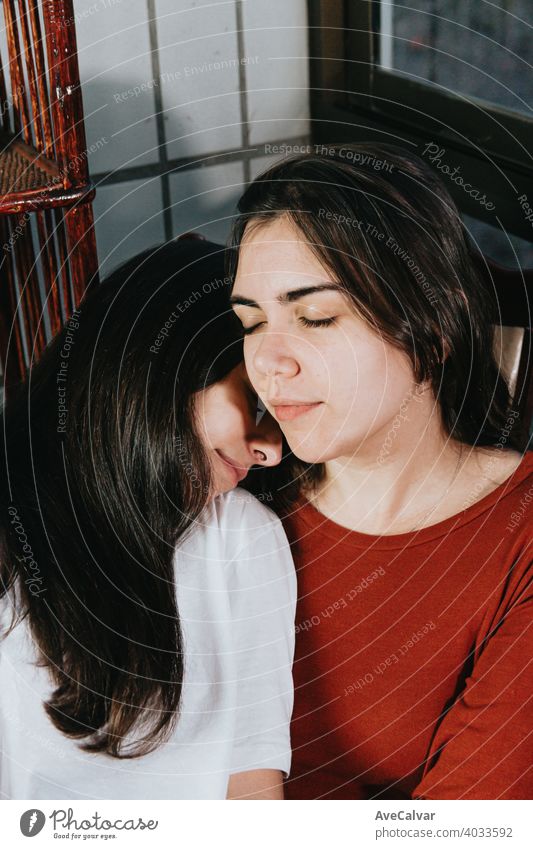 Lesbian couple resting on each other with the eyes closed relaxing affectionate answering cuddling embracing friends girls headshot horizontal kissing laughing
