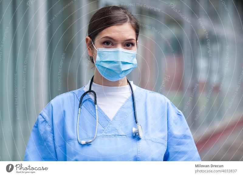Young worried stressed anxious female EMS key worker doctor portrait outside hospital young serious woman face mask medical healthcare ambulance caucasian