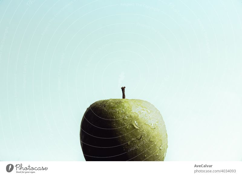 A super close up of a delicious apple with some water drops over it over a light background with copy space group many horizontal health wet ahead colours