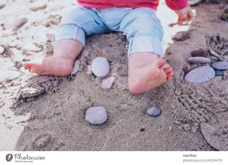 Little baby discovering the sand and sea holidays travel beach real curious playful sitting 8 months grow up life lifestyle cute adorable lovely jeans sun sunny
