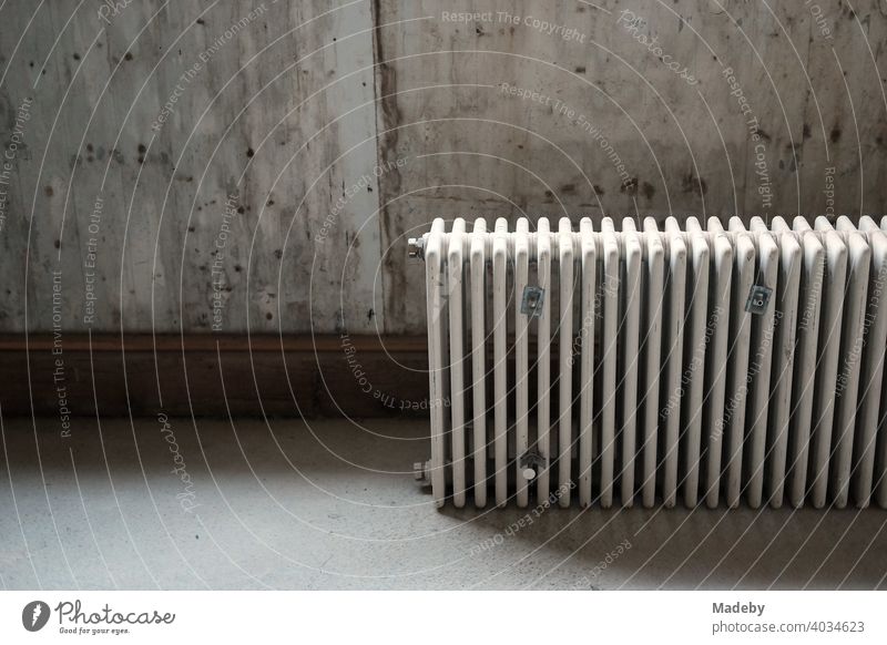 Old radiator in front of grey concrete wall during the renovation of a farmhouse in Rudersau near Rottenbuch in the district of Weilheim-Schongau in Upper Bavaria