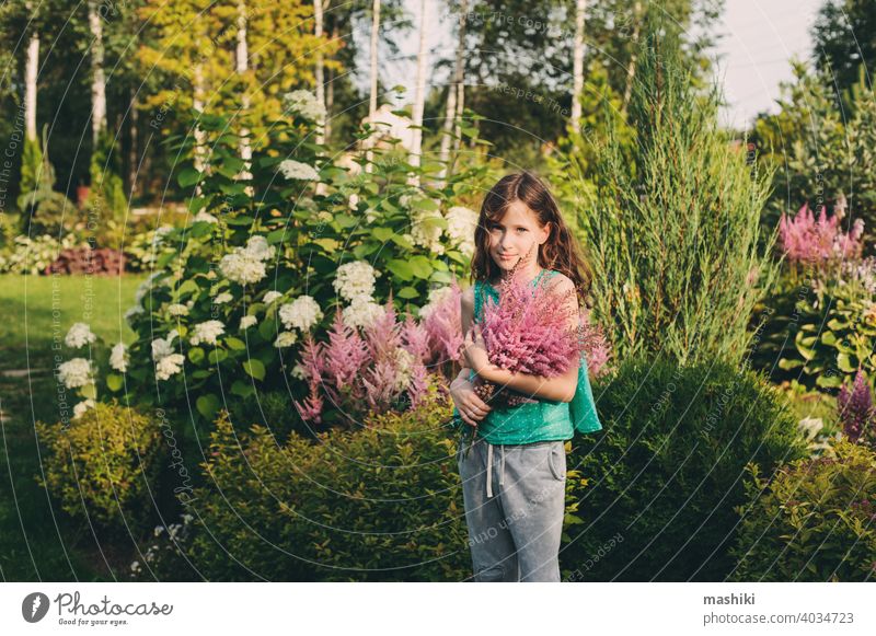 happy kid girl picking bouquet of astilbe flowers in summer garden child nature childhood outdoor happiness green cute fun little playing smiling young portrait