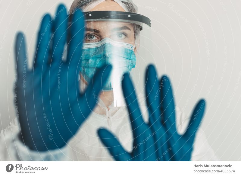 Healthcare worker with shield and mask showing stop gesture cure disease doctor england epidemic experiment experimental france germany gloves hand health