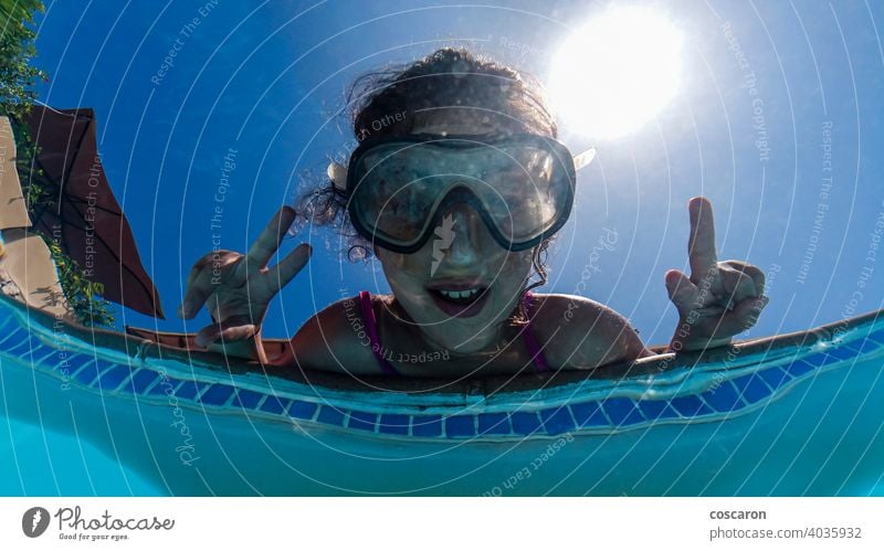 Little girl on a poolside. View from below. active bikini blue bubbles child childhood diving enjoy face fun funny goggles happiness healthy kid kids learn