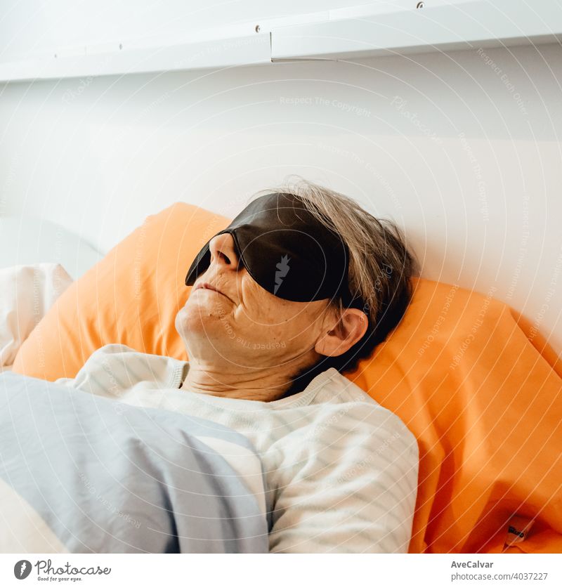 An old lady sleeping using a face mask in a modern bedroom woman senior night grey-haired morning pajama grandmother expression rest pink portrait beautiful