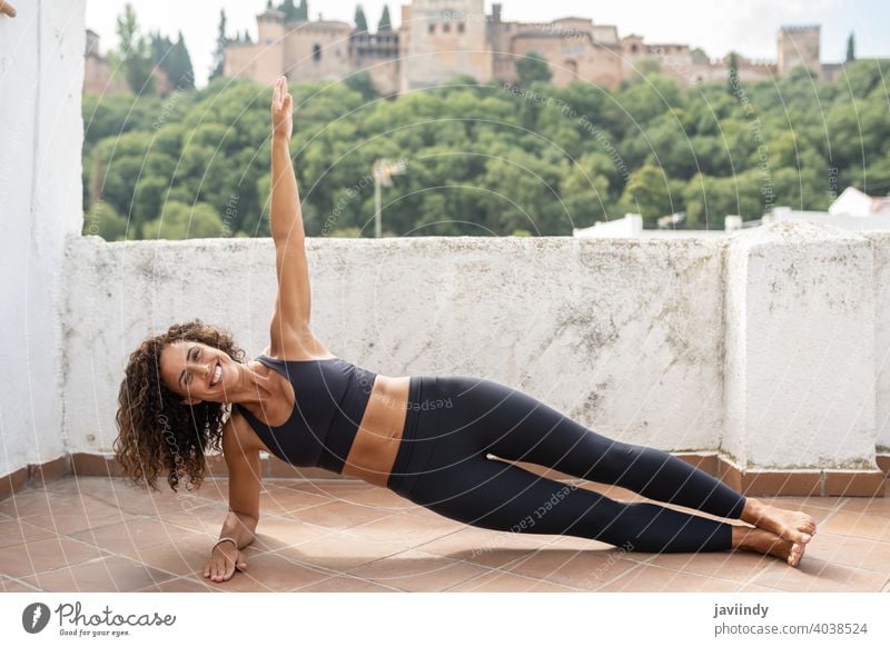 Middle-aged woman with fitness body working out on the terrace of her house training workout plank planking 40s middle age sportswear lifestyle person female