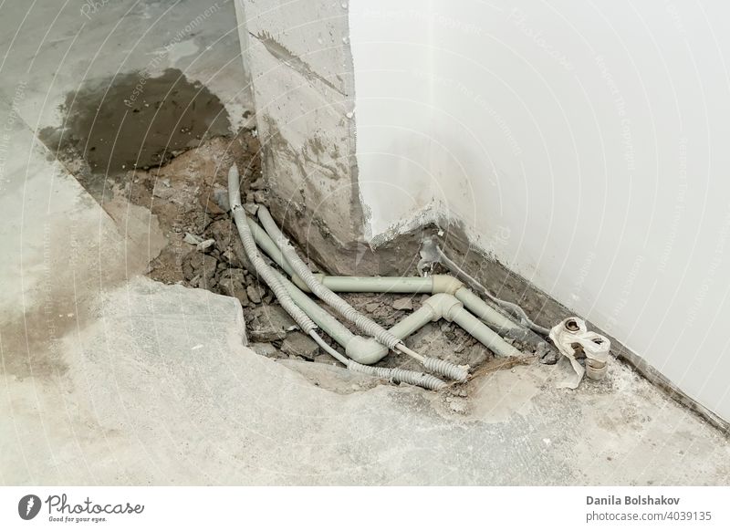 Repair of plastic polypropylene gray sewer pipes in hole in cement floor in apartment. Concept of pipe replacement, water leakage, transfer of water supply