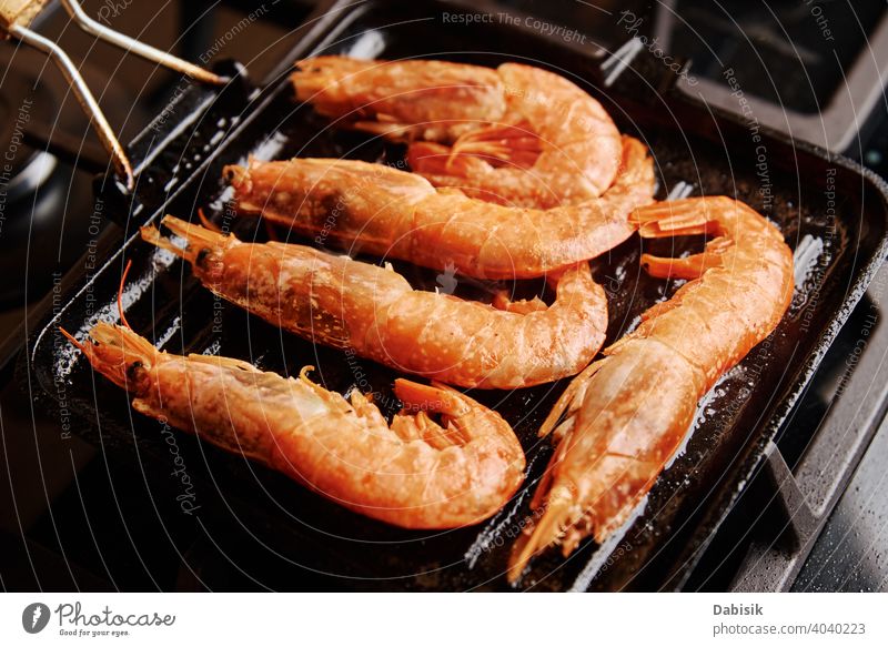 Grilled large shrimps with lemon and spices on the grill pan prawns seafood red background dark black shellfish dish tiger cooked crayfish eating gourmet