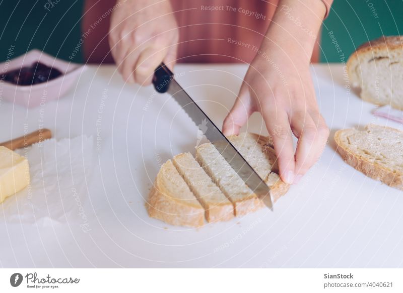 Woman cutting bread at  kitchen hands breakfast making green background dress marble cooking home toasted spoon table calories eating young protein jar