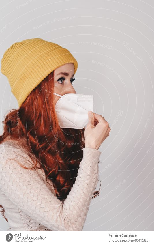 Redhead young woman in yellow hipster beanie cap pulls FFP-2 mask away from face ffp2 Mask Mask obligation breathe deeply gasp Breathe Beanie hat Cap Yellow