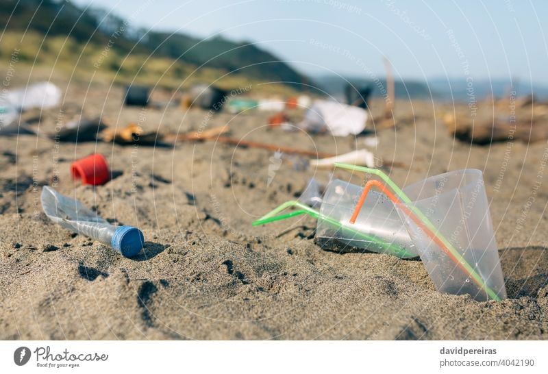 Dirty beach landscape full of waste trash garbage straws disposable cups plastic contaminated sand dirty environment nature pollution coast plastic lid rubbish