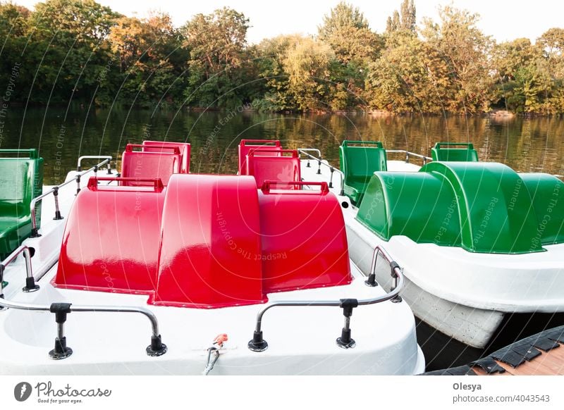 Pedal boats in green and red are moored or parked at a small pier at the mouth of the river horizontal silhouette stormy health luxury paradise recreational