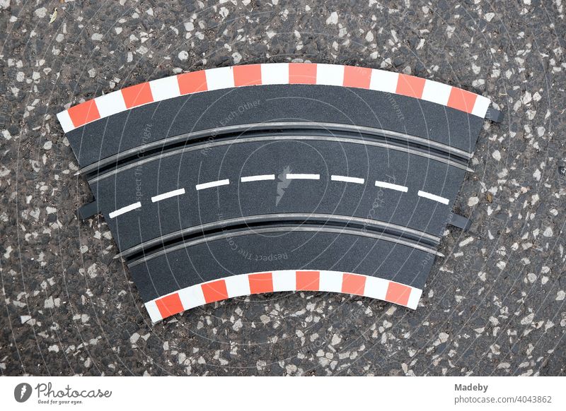 Curved part of a car racetrack with dotted white center line on grey asphalt at the flea market at the Golden Oldies in Wettenberg Krofdorf-Gleiberg near Gießen in Hesse, Germany