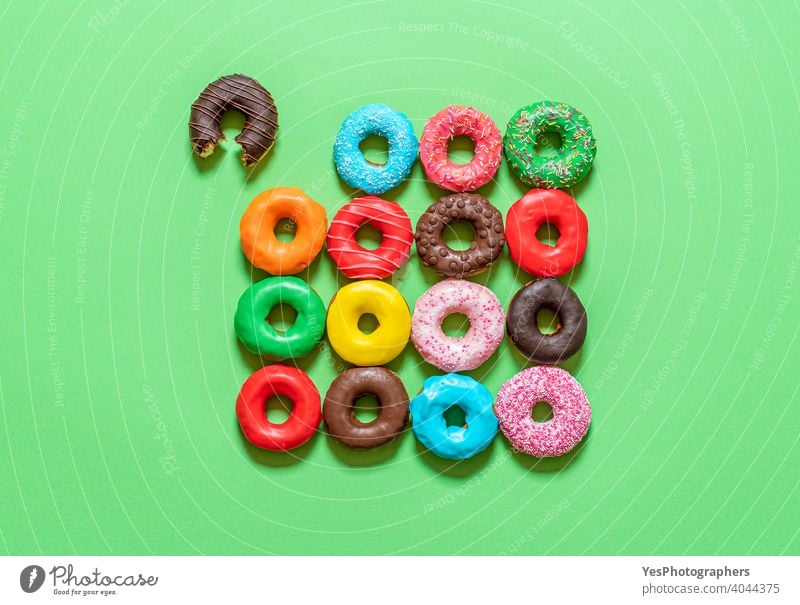 Chocolate donuts with multicolored icing, top view on a green background. above view aligned assorted baked bitten blue cake chocolate colorful cuisine cut out