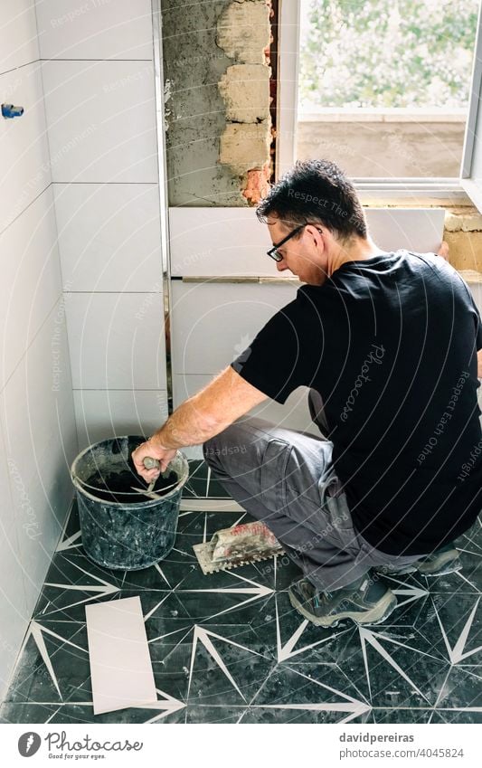 Mason taking cement from bucket to lay bathroom tiles mason reform wall concrete spatula diy masonry worker caucasian man male one people person builder tools