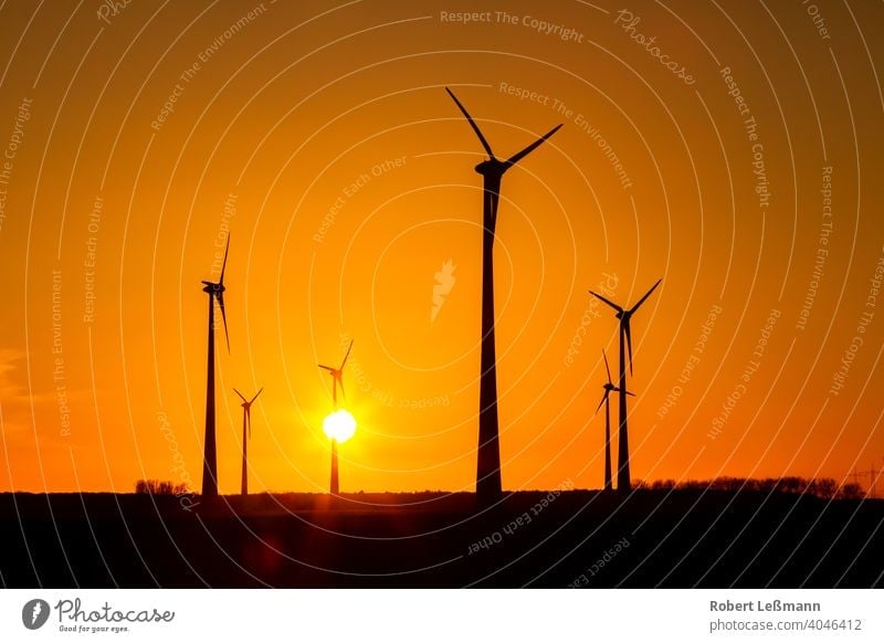 many wind turbines at sunset stand on a field and produce electricity windmills eco-power Eco-friendly Climate protection Sunset Electricity Silhouette