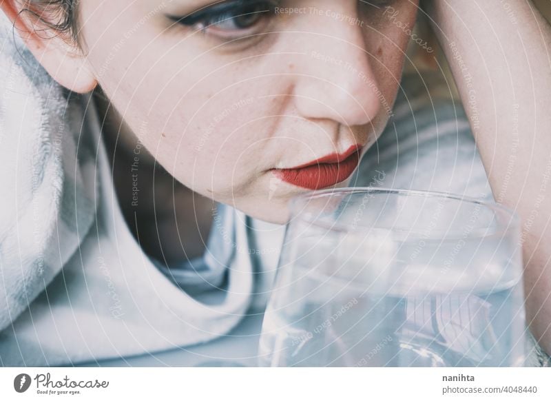 Portrait of a young woman hidden by a glass with a transparent drink depression blue sad mental health psychology sadness depressive cold white reflection