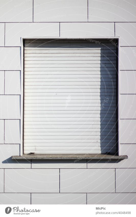 White house facade, a window with closed white roller shutter Facade white background Roller shutter Closed lockdown Shutter shadow cast clear Empty Vacancy