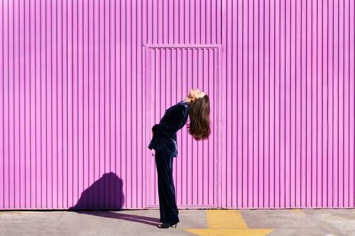 Woman wearing blue suit posing near pink shutter. woman hairstyle fashion model building blind fuchsia purple moving girl person lifestyle female urban