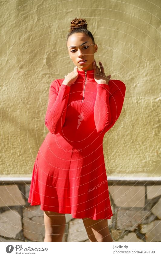 Young black woman in red dress with a serious expression in urban background. bow hairstyle model beauty fashion pretty portrait girl young female person lady