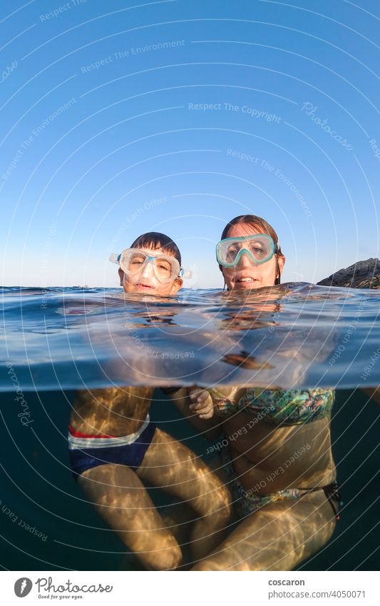Mother and son snorkeling on a clear water beach blue boy cheerful child childhood diver diving equipment face family female fun half kid leisure little mask
