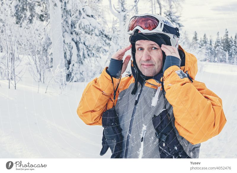 Caucasian man snowboarder in white helmet and overalls on background snowy forest. Winter active rest. Vacation in the mountains. Healthy lifestyle caucasian