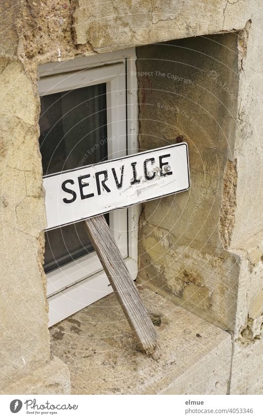 A rather ramshackle sign reading "SERVICE" leans in front of a small window of a slowly decaying house / Customer Service service Window dilapidated