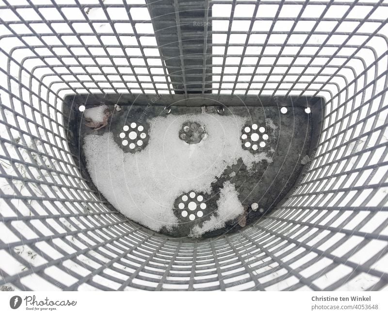 View from above into a snow-covered empty litter bin made of metal lattice with a punched flower pattern on the bottom Litter bin rubbish bin waste Trash Snow
