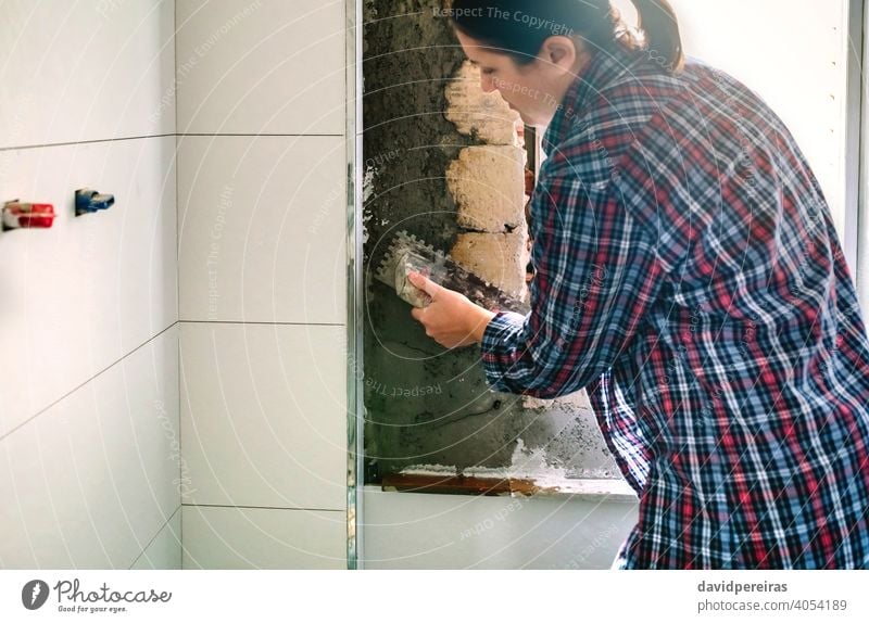 Female mason leveling cement with a trowel female smooth over concrete tile bathroom copy space construction masonry tiled spread work one people person