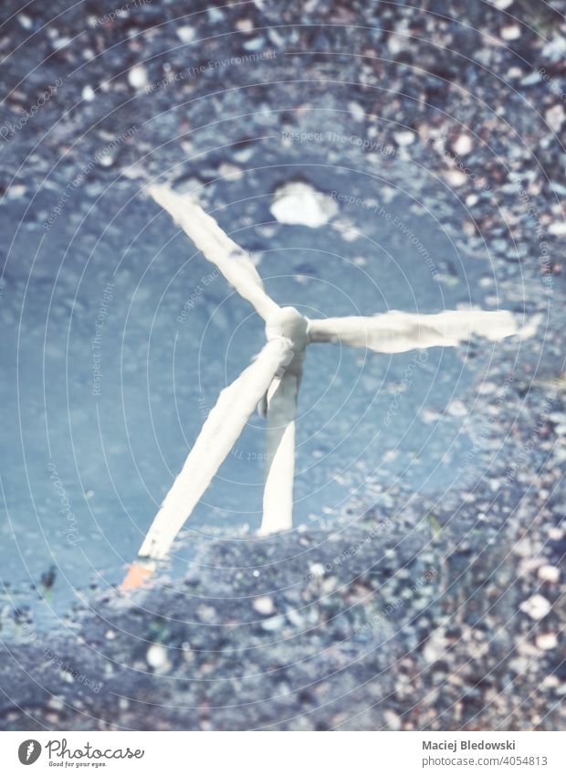 Blurred picture of a windmill turbine reflection in a puddle, abstract conceptual background. water blurred environment de focused eco energy business industry