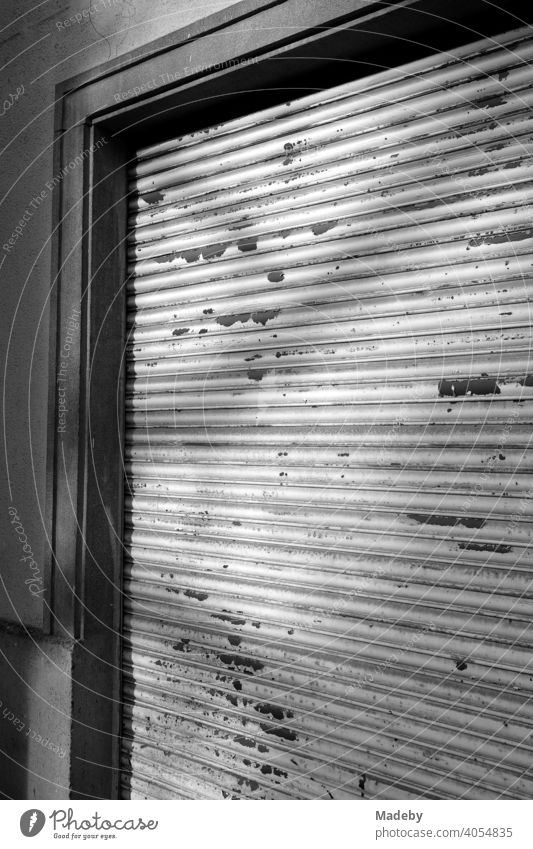 Lowered roller shutter with peeling paint in front of a shop in the city centre of Frankfurt am Main in Hesse, photographed in classic black and white
