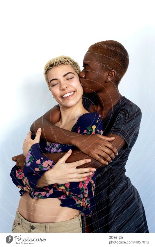 Joyful ladies kissing and embracing togetherness, being of different of races, dressed in casual clothes. couple ethnicity friendship multiethnic smiling two