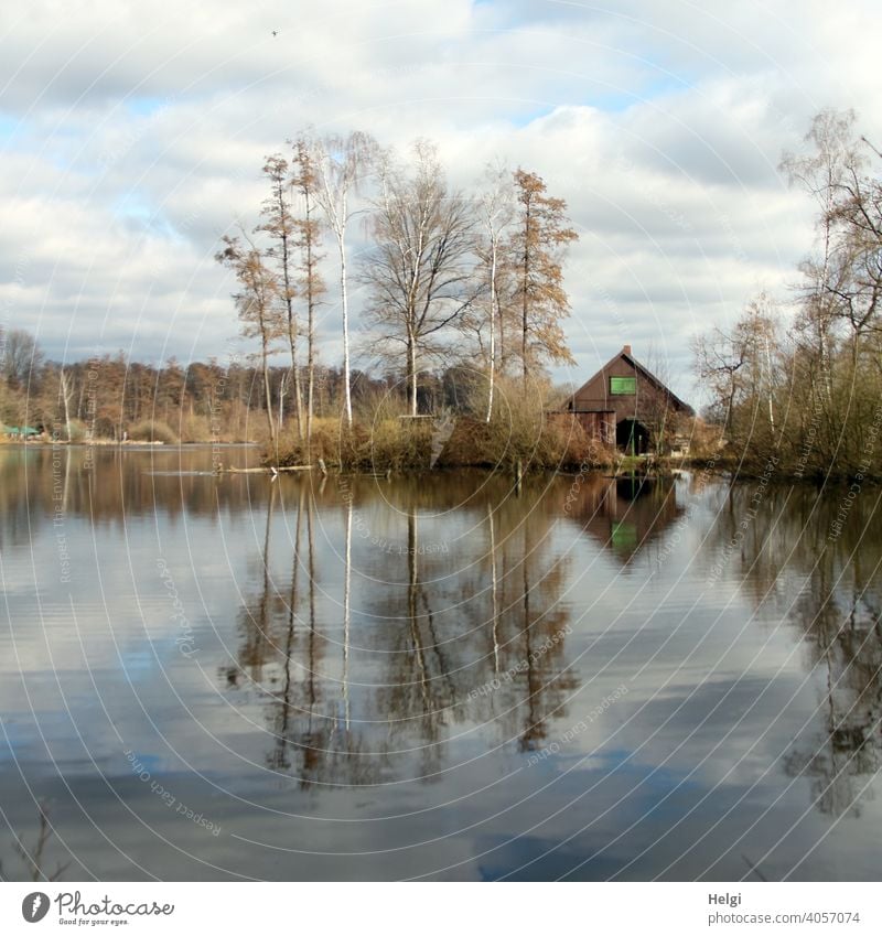 old wooden hut at the lake with trees , clouds in the sky and reflection in the water Wooden hut House (Residential Structure) Hut Building Old Water Lake