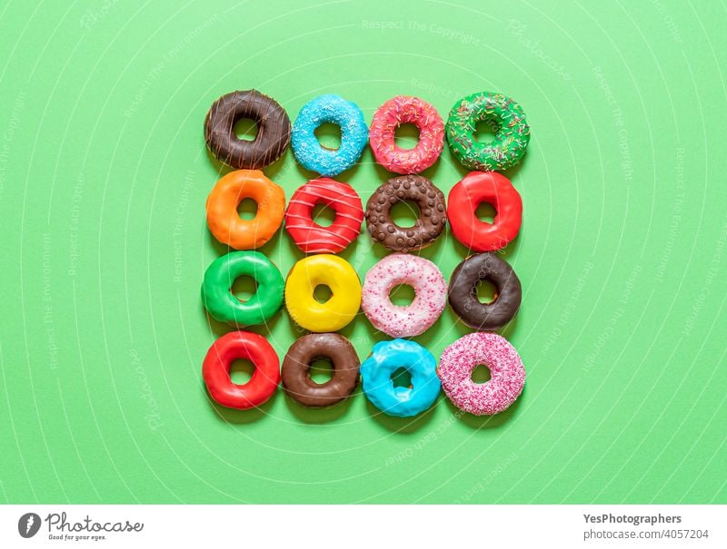 Donuts with icing top view. Multicolored doughnuts on a green background. above view aligned assorted baked blue cake chocolate colorful cuisine cut out