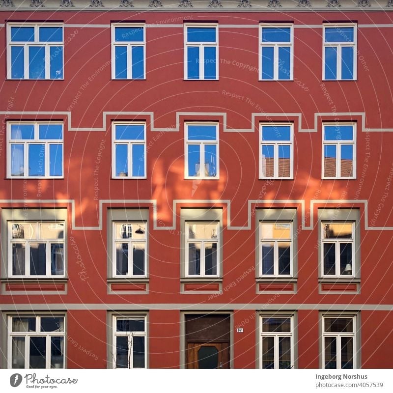 Red house facade with patterns around the windows urban exterior glass geometric building architecture rows edifice design architectonic outdoors structure