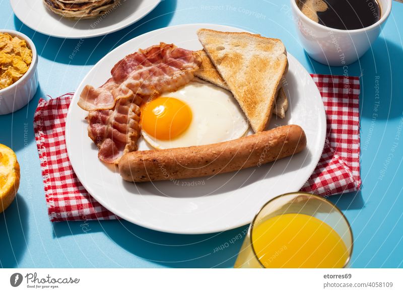 Traditional American breakfast on blue background amrican bacon bread butter cereals dish egg fat food fried fruit juice nutrition orange pancakes plate protein