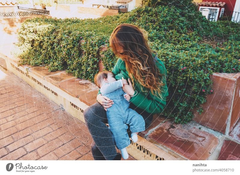Young woman breastfeeding her baby outdoors in a sunny day young mother mom family green holidays leisure health blonde care childhood parenthood babyhood