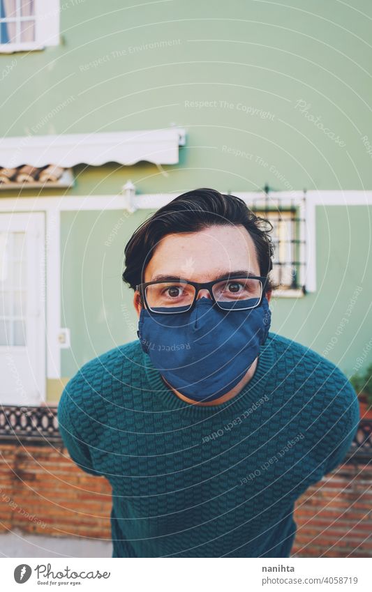 Young man wearing a face mask against a green wall portrait male covid coronavirus glasses flu influencia risk responsible health healthy eye wear outdoors