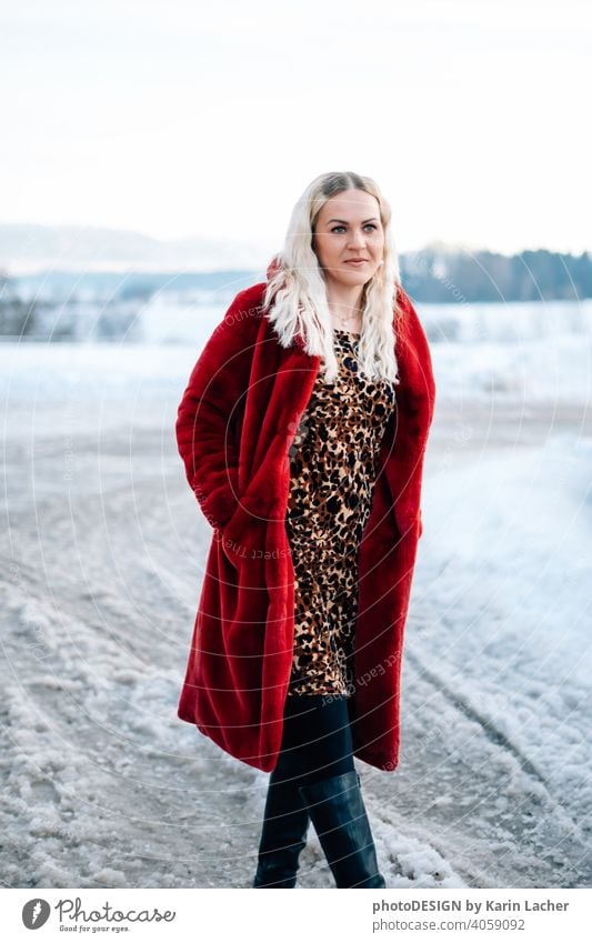 young woman 30 years in snow with red coat and leopard dress blond hair curly happy hopeful street fashion Woman Dress leopard Model outdoor Snow Snowscape