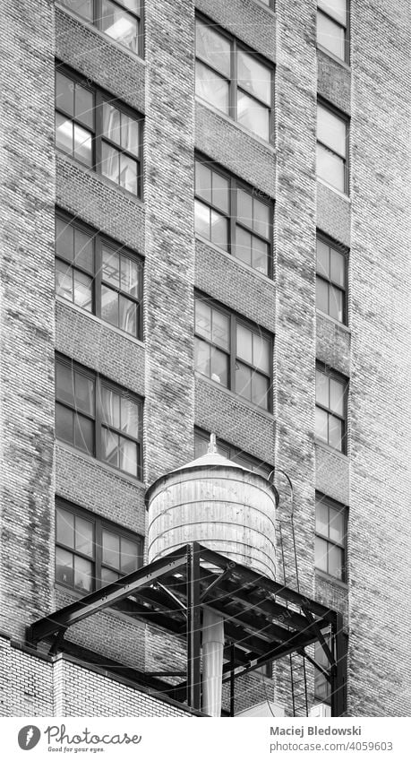 Black and white picture of water tower on a roof of an old building in Manhattan, New York City, USA. city water tank black and white architecture NYC B&W view