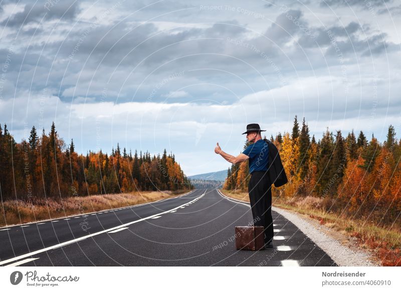 Life artist and dropout hitchhikes along a lonely country road with his thumb up in the air hedonist Nonconformist In transit Joie de vivre (Vitality) Adventure