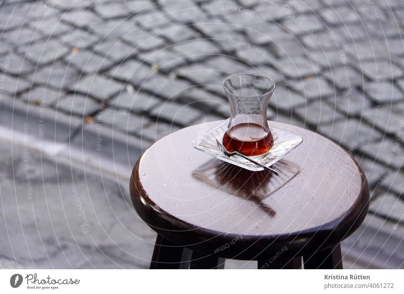 a glass of tea stands on a stool at the roadside Cay Tea Tea glass Bar stool out off Street tea break Turkish Turkish Tea traditionally Black Black tea Glass