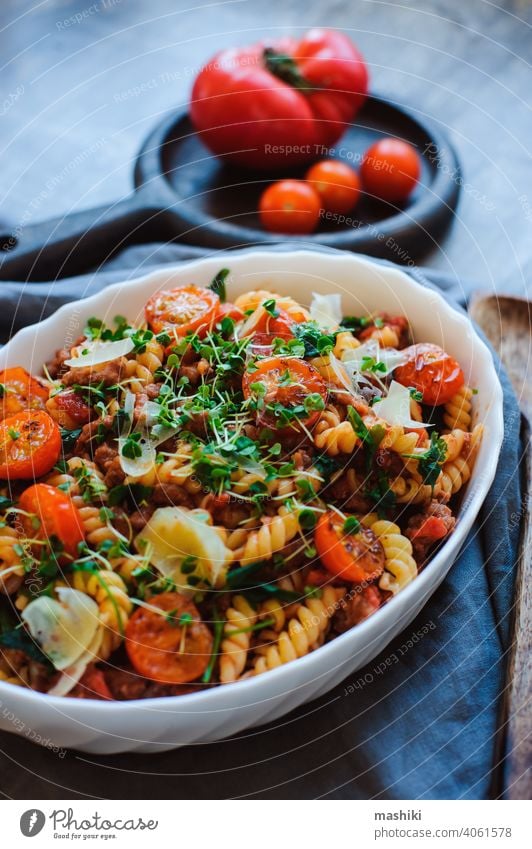 cooking tasty comfort food - italian fusilli pasta baked with meat sauce, cherry tomatoes and cheese lunch dinner plate dish vegetable basil cuisine red cooked
