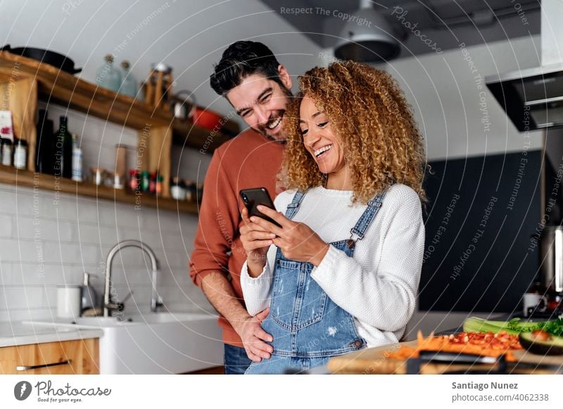 Couple looking at a smartphone in kitchen. middle age couple love cooking home cozy caucasian relationship preparing female happy person stove woman beautiful