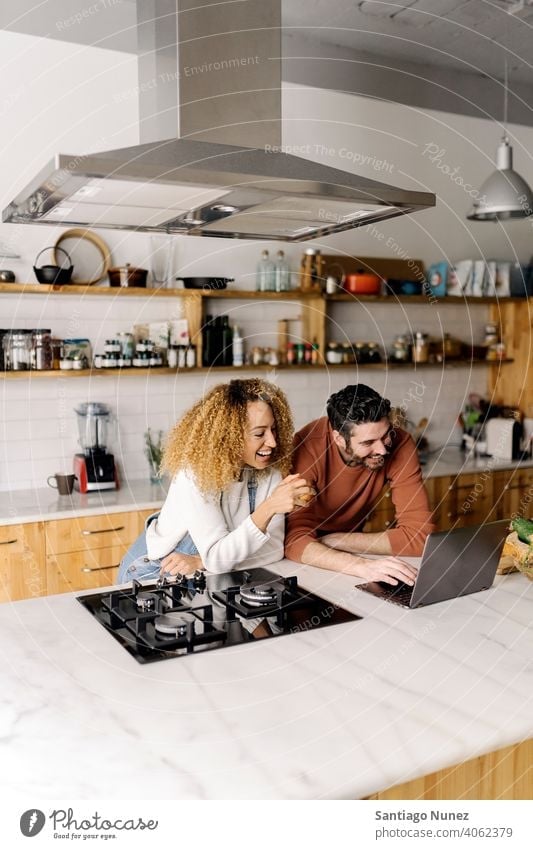 Couple looking at laptop in kitchen. middle age couple love cooking home cozy caucasian relationship preparing female happy person stove woman beautiful girl