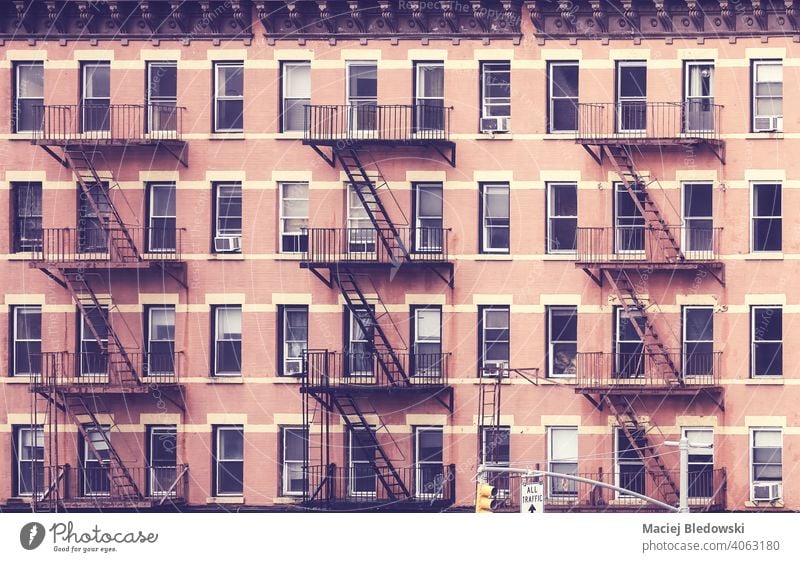 Old tenement house building with fire escapes, color toned picture, New York City, USA. city NYC retro symbol old residential home effect apartment Manhattan